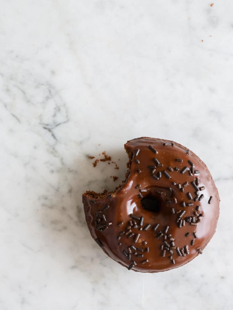 A baked chocolate donut with a bite taken out.