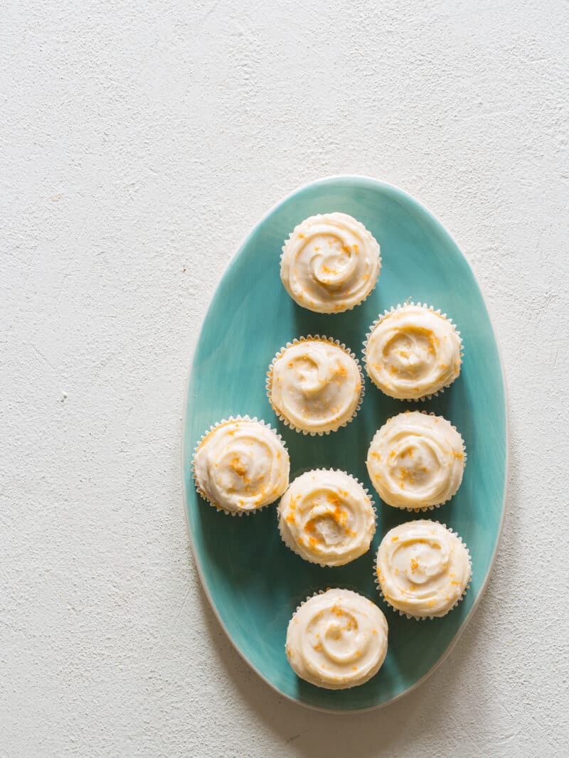 A plate of butter cupcakes with grapefruit buttercream frosting and grapefruit zest.