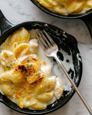 A close up of creamy skillet mac and cheese, half eaten with a fork.
