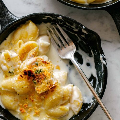 A close up of creamy skillet mac and cheese, half eaten with a fork.