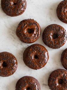 Baked chocolate doughnuts with chocolate frosting and sprinkles.