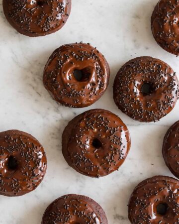 Baked chocolate doughnuts with chocolate frosting and sprinkles.