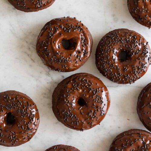 Baked chocolate doughnuts with chocolate frosting and sprinkles.