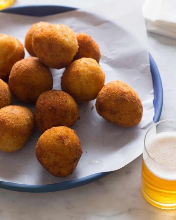 Coxinha on a blue plate with a drink.