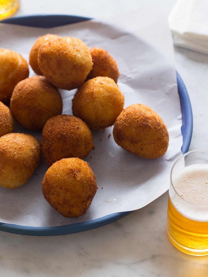 Coxinha on a blue plate with a drink.