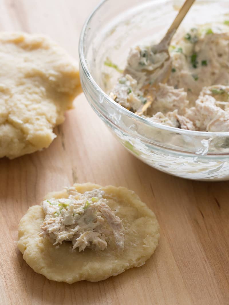 A close up of a bowl of filling, dough, and coxinha being assembled.