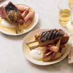 Plates of grilled rack of lamb with creamy feta horseradish sauce, roasted radishes, and drinks.