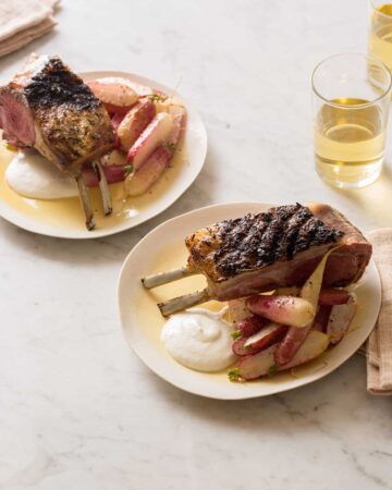 Plates of grilled rack of lamb with creamy feta horseradish sauce, roasted radishes, and drinks.