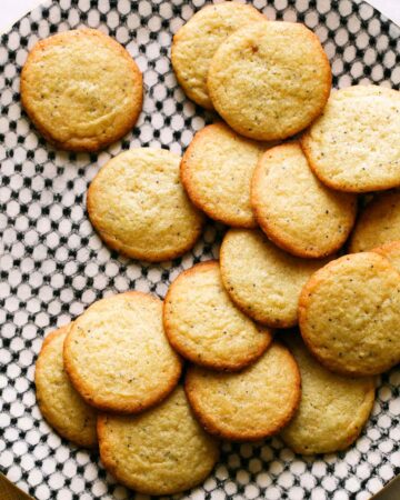 Pile of chewy lemon cookies on black and white plate.