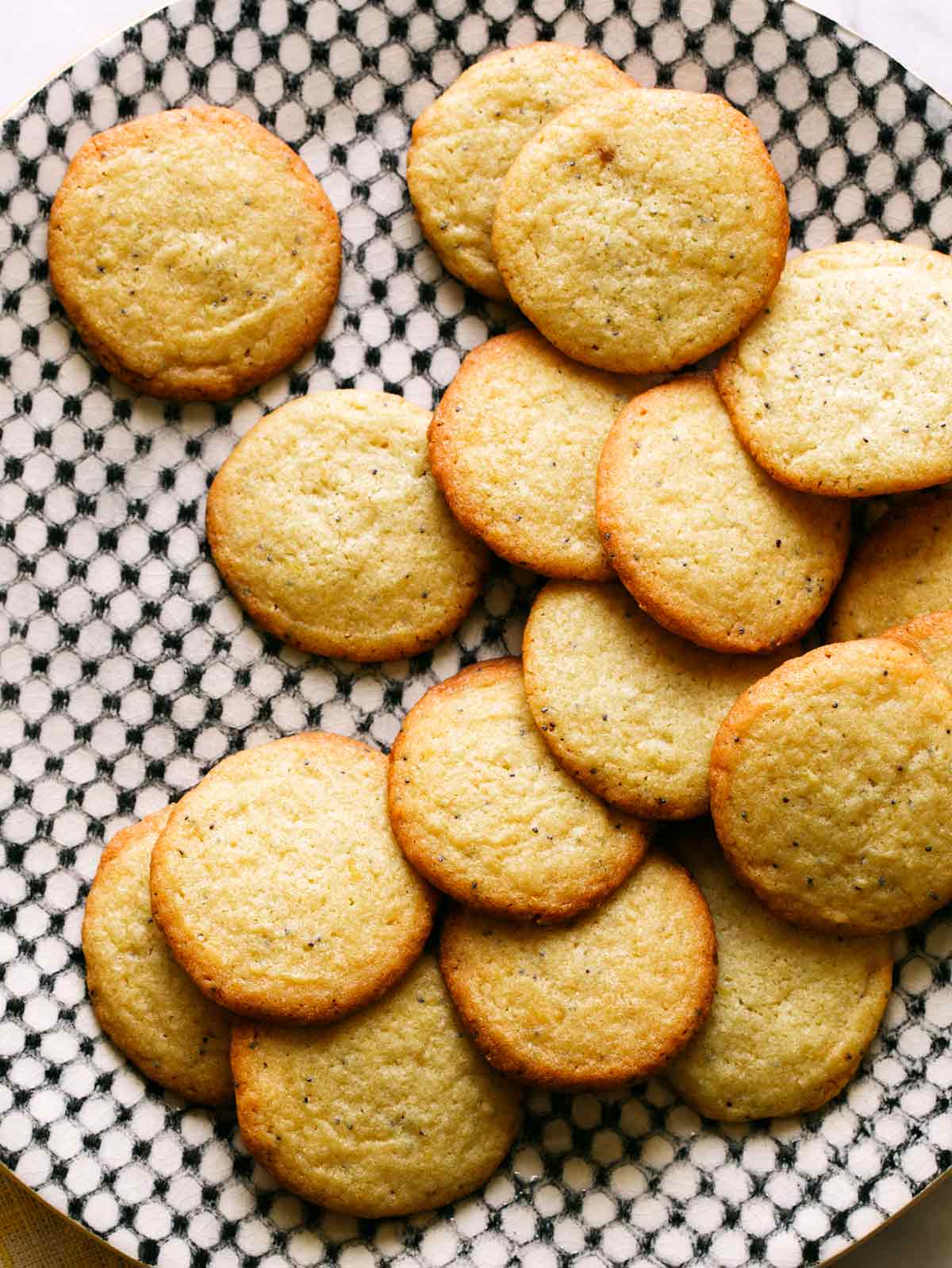 Pile of chewy lemon cookies on black and white plate.