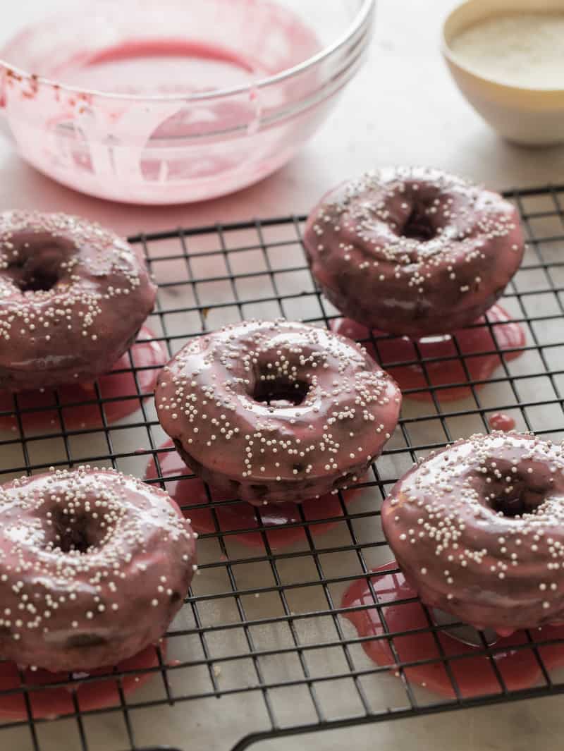 Chocolate baked donuts with a bowl of plum glaze in the background.