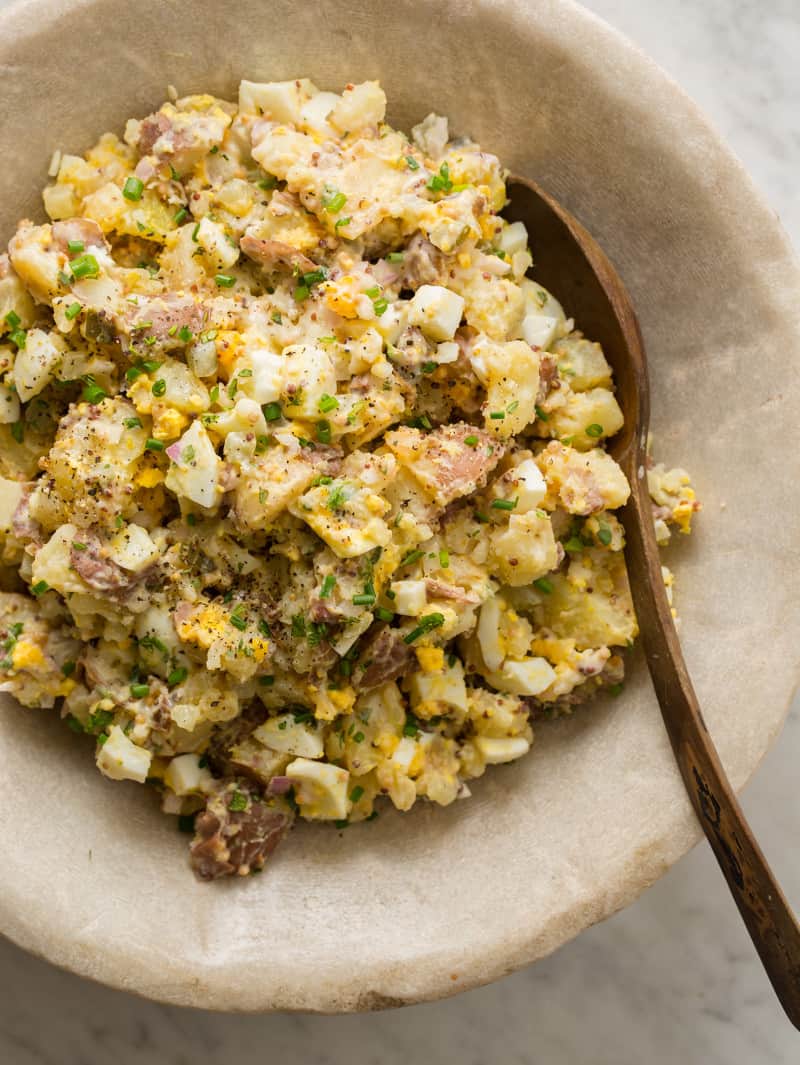 Creamy Potato Salad in a bowl overhead with a wooden spoon in it. 