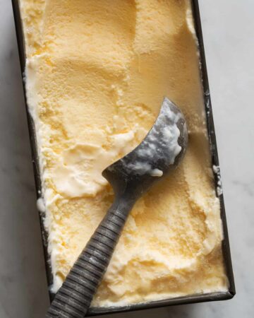 A close up of salted cantaloupe ginger ice cream with an ice cream scoop.