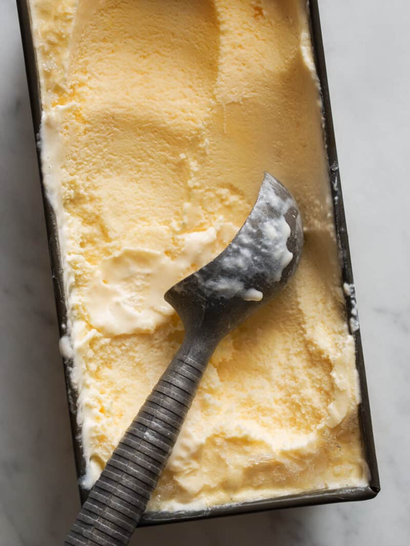Salted Cantaloupe and Ginger Ice Cream in a dish with an ice cream scoop. 
