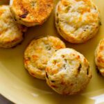 A close up of roasted hatch and cheddar biscuits on a yellow plate.