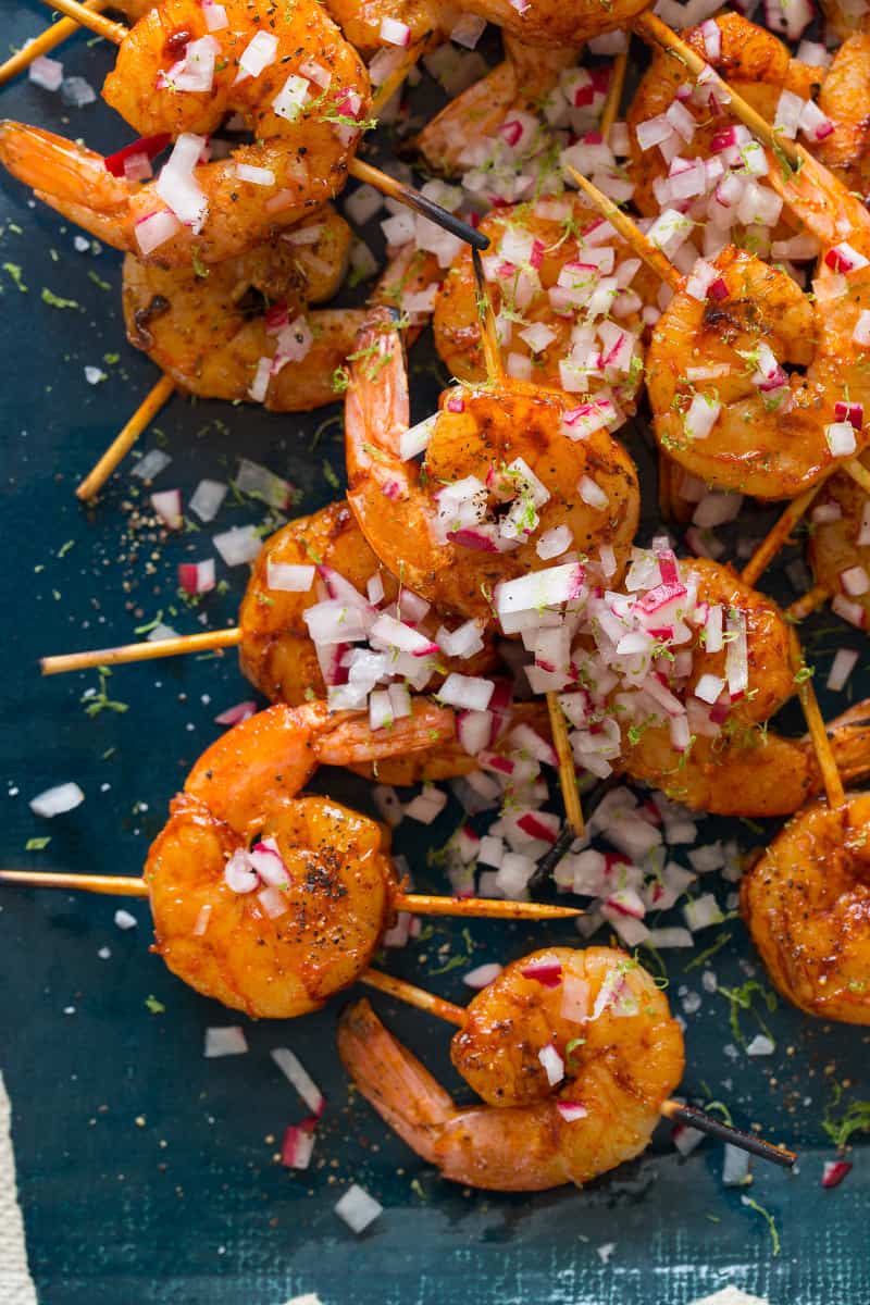A close up of smoked paprika and garlic shrimp skewers topped with onion.