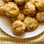 A plate of roasted hatch and cheddar biscuits on a yellow gingham cloth.