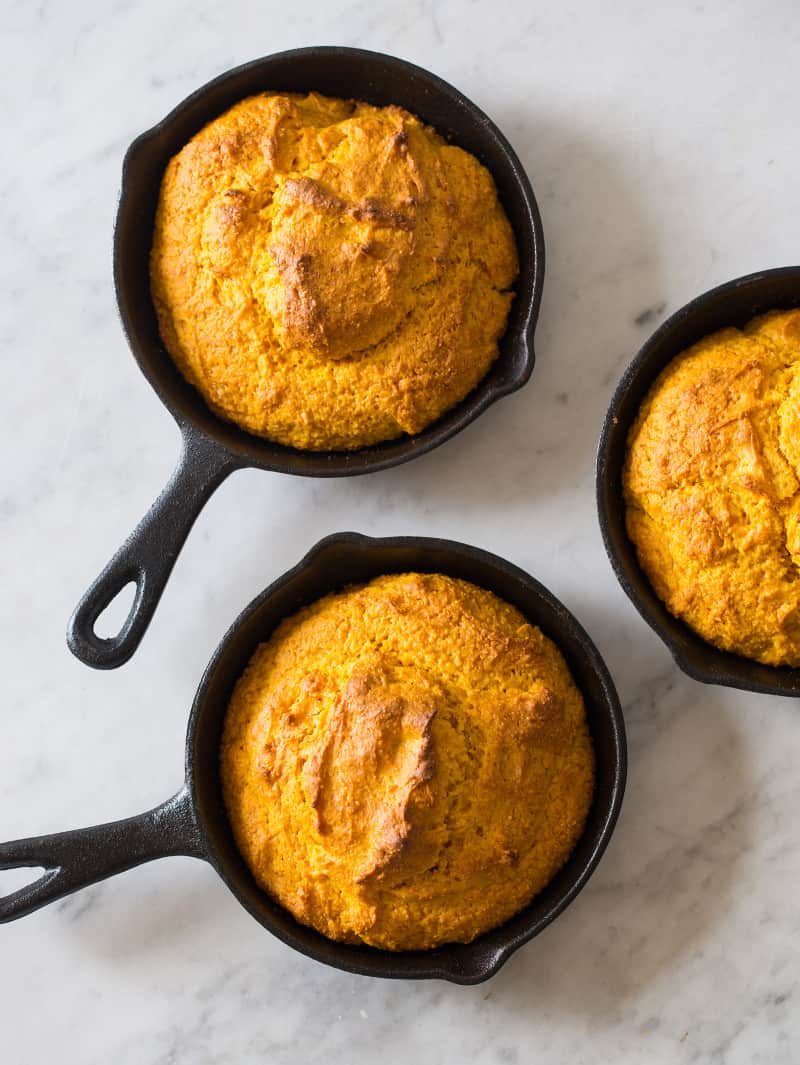 Three small skillets of pumpkin cornbread freshly baked. 