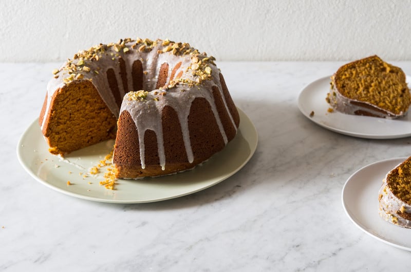 Pumpkin bundt cake with two slices taken out sitting on two plates next to it. 