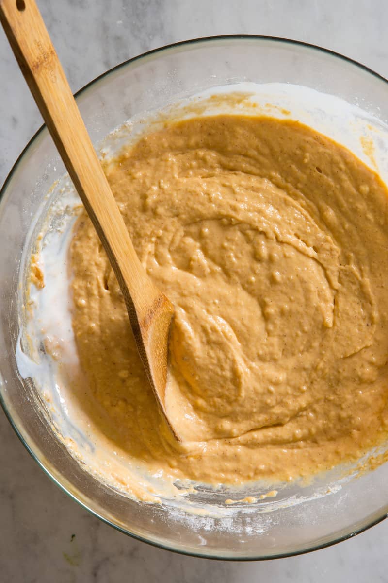A close up of a bowl of waffle batter with a wooden spoon.