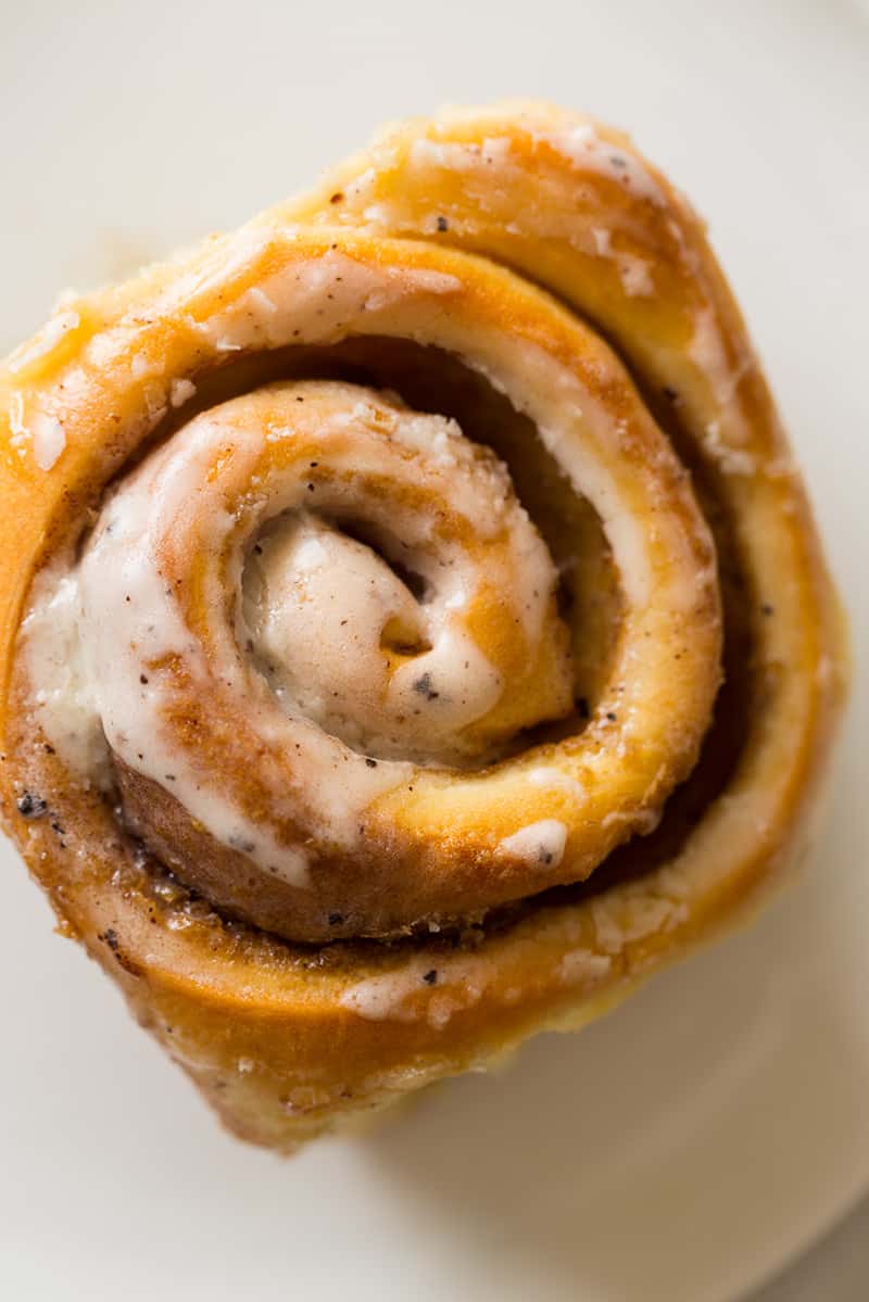 A close up of a beautiful cinnamon roll overhead on a plate. 