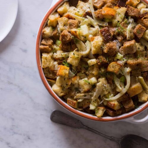 A bowl of apple and fennel stuffing with a spoon.