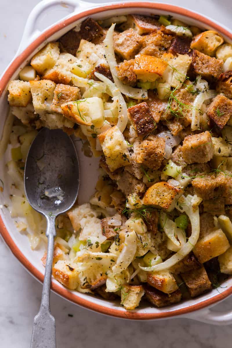 A close up of a dish of fennel apple stuffing with a spoon.