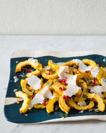 A turquoise and white platter of honey roasted delicata squash.