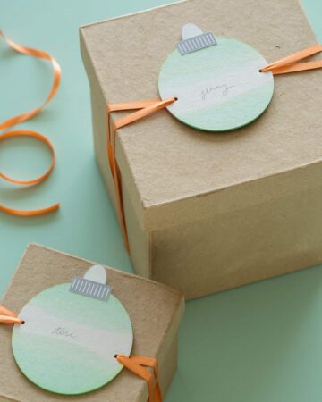 Dip dye ornament gift tags tied onto brown gift boxes.