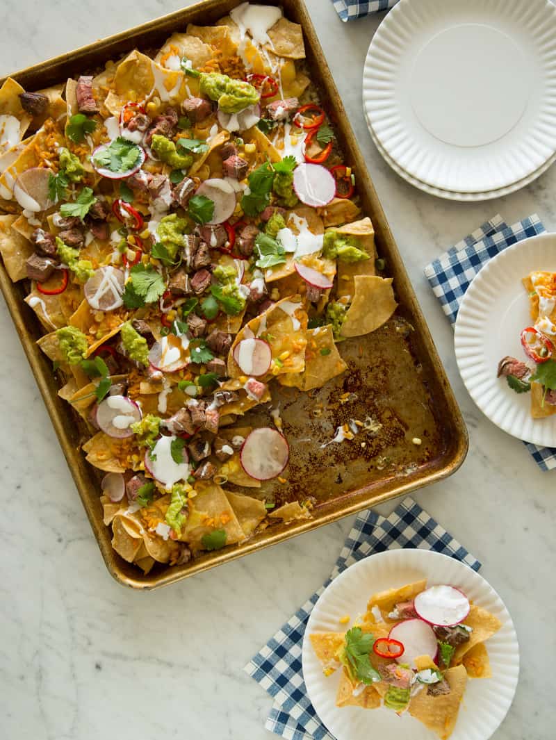 Carne asada nachos with servings on small plates.