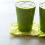 A close up of coconut kale smoothies with green printed paper napkins.