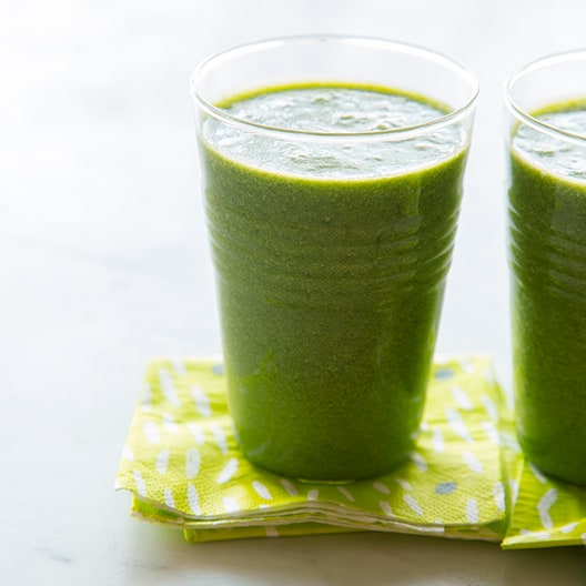 Two coconut and kale smoothies on napkins. 