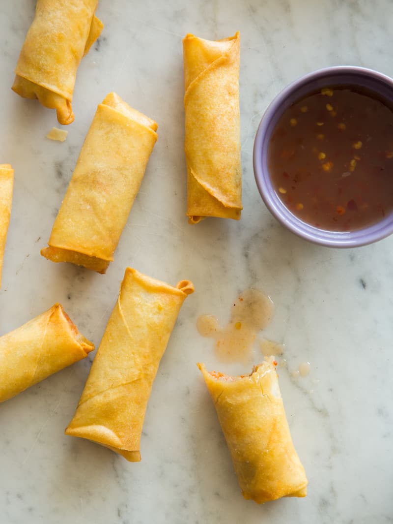 Vietnamese pork and shrimp egg rolls on a kitchen counter with a bite taken out of one. 