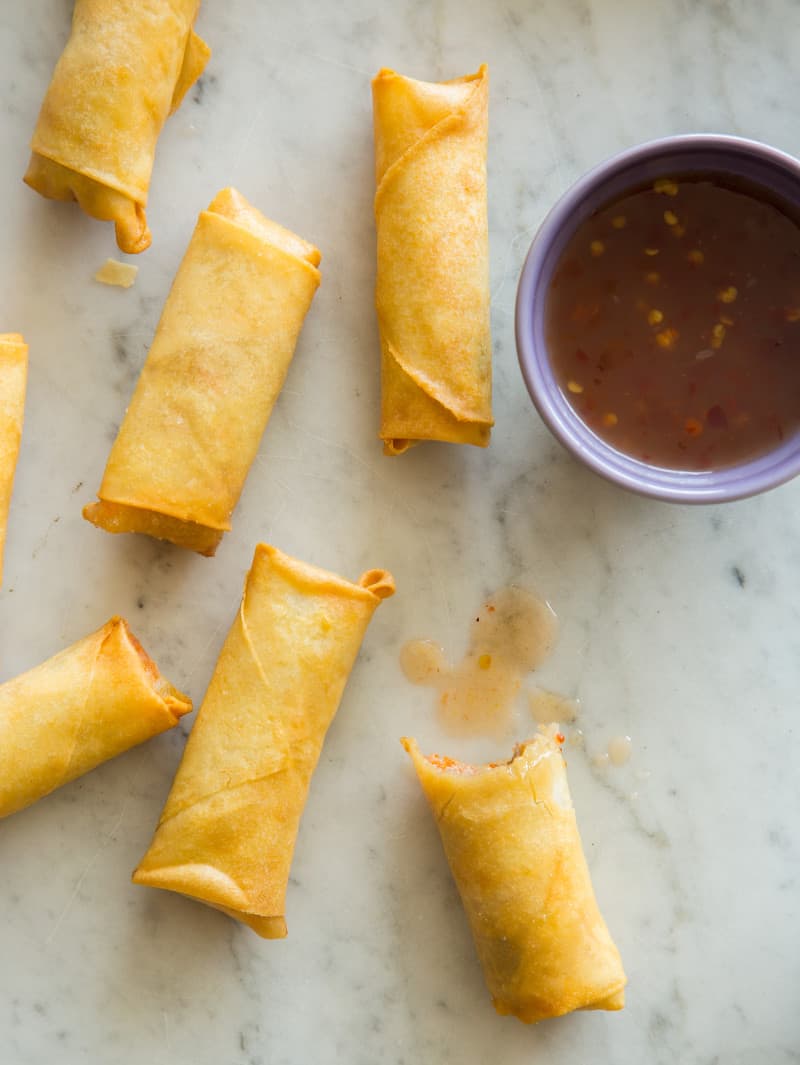 Vietnamese pork and shrimp egg rolls on a kitchen counter with a bite taken out of one.