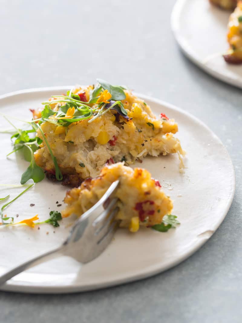 A freshly made crab cake recipe on a plate with a fork. 