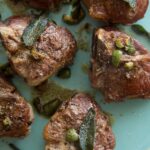 A close up of garlic and anchovy roasted lamb chops with castelvetrano and sage browned butter.