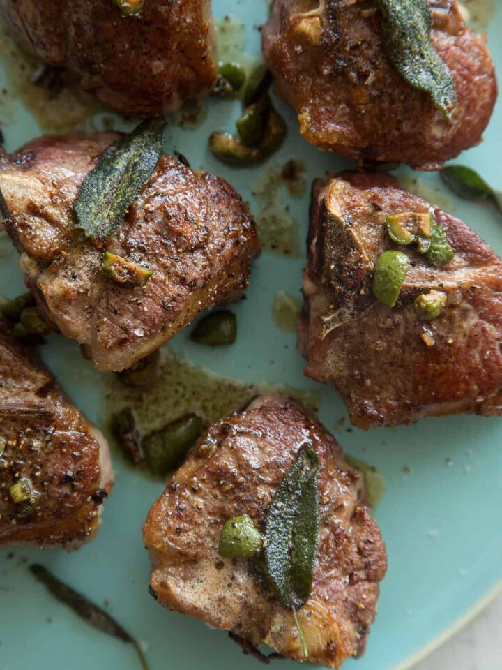 A close up of garlic and anchovy roasted lamb chops with castelvetrano and sage browned butter.