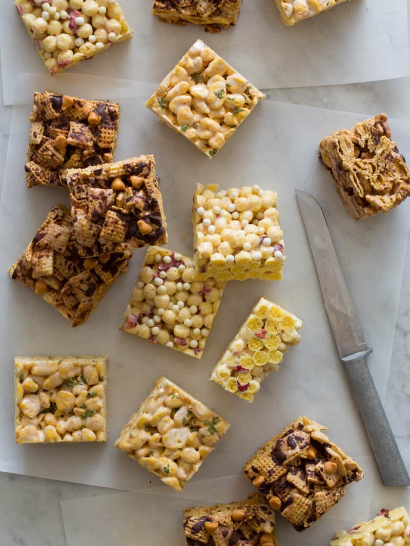 Marshamllow cereal treats on a surface with a knife and parchment. 