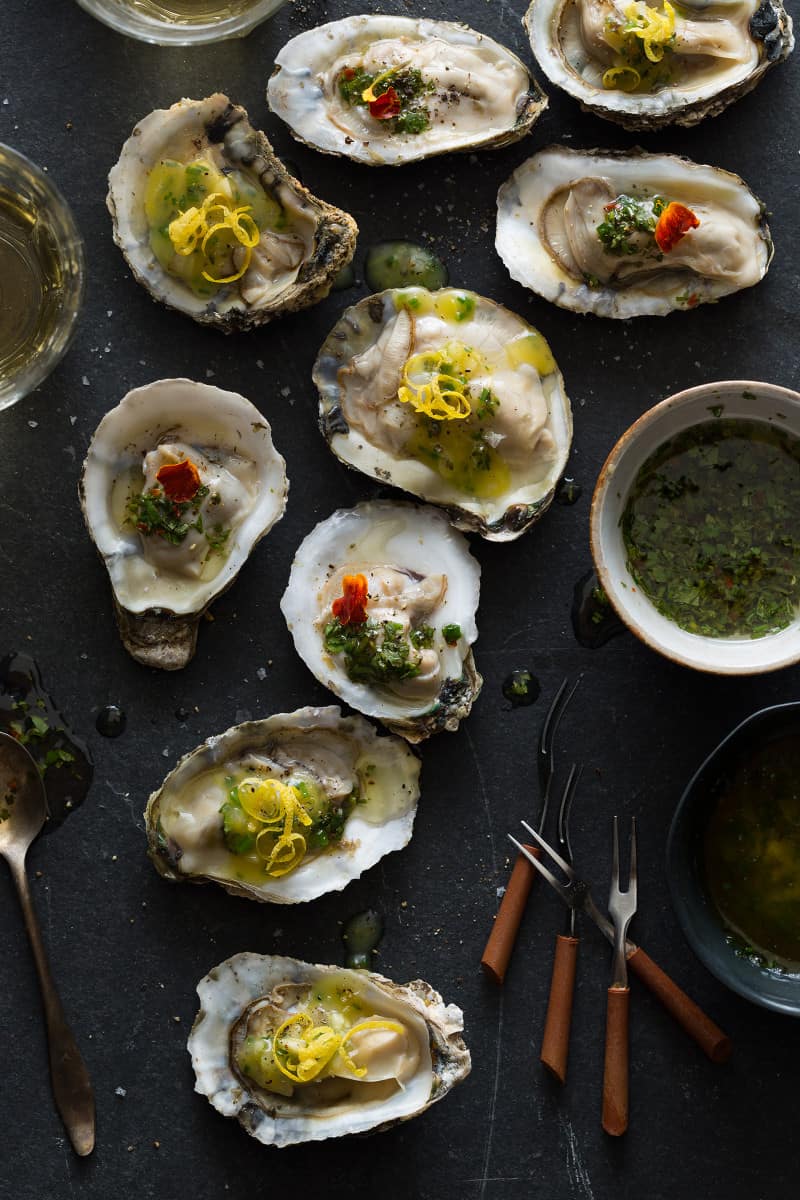 Roasted oysters on a surface with dipping sauces. 