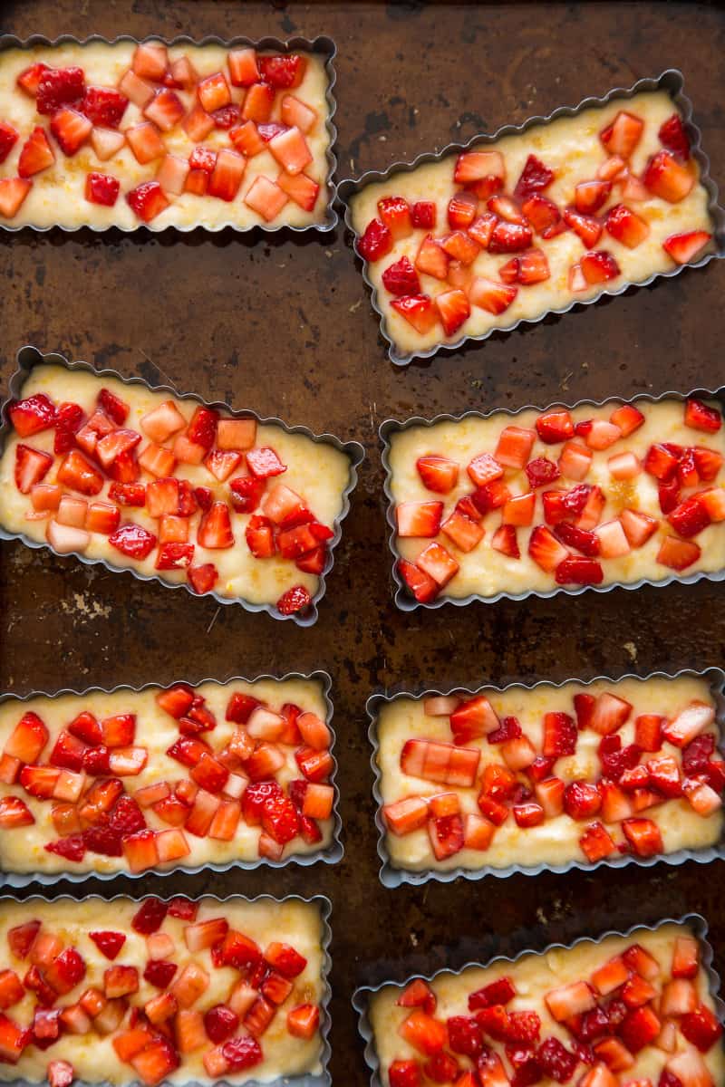 Mini strawberry cobblers in mini tart pans on a baking sheet ready to put into the oven. 