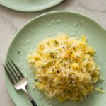 Plates of spaghetti quash with goat cheese and garlic sauce and a fork.