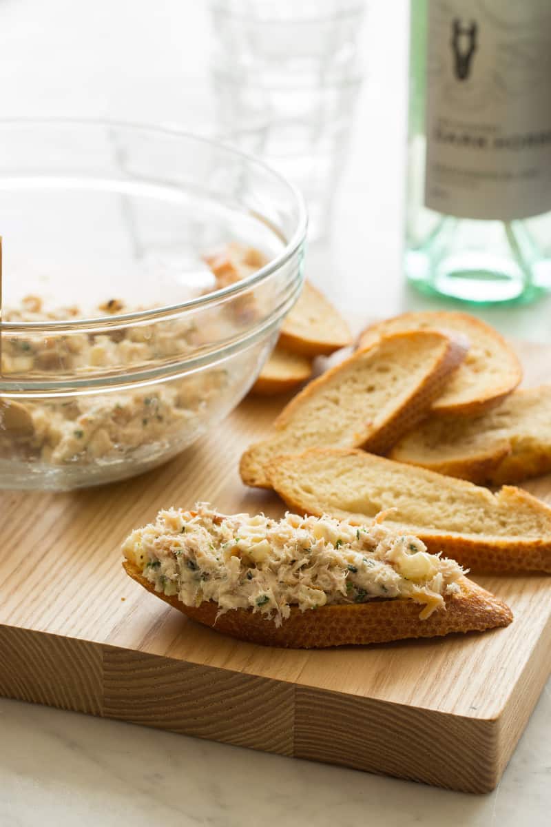 A clear bowl of smoked trout being put on toast.