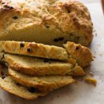 A close up of a sliced loaf of Irish soda bread with dried blueberries.