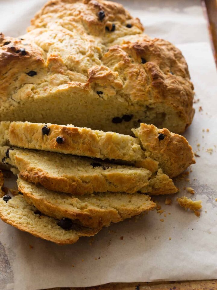 A close up of a sliced loaf of Irish soda bread with dried blueberries.