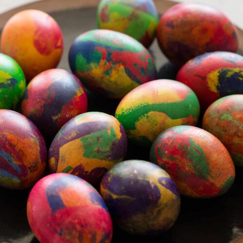 A plate of colorful painterly dyed Easter eggs.