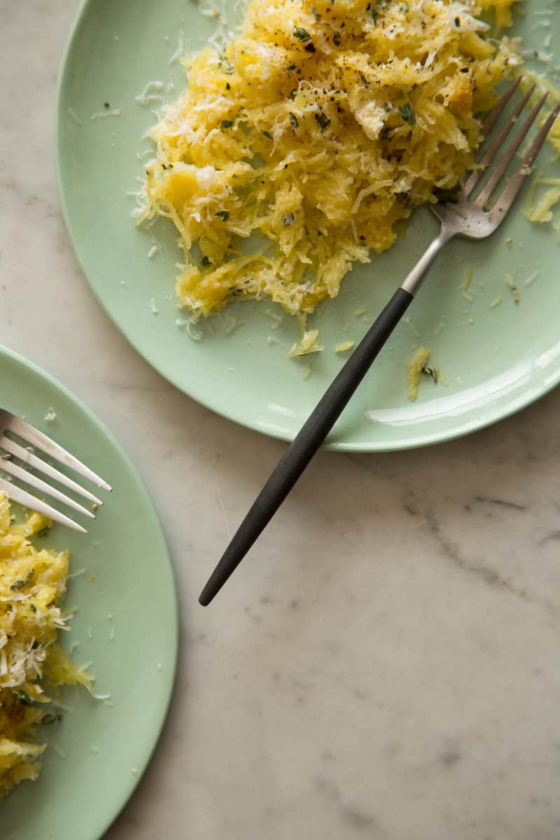 Plates of spaghetti quash with goat cheese and garlic sauce and forks.