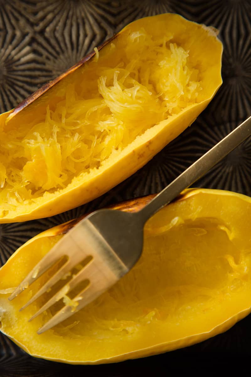 A close up of spaghetti quash with a fork "fluffing" the spaghetti.