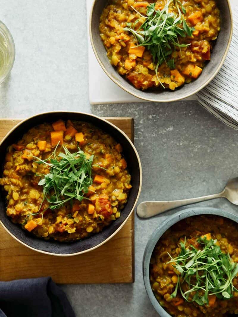 Masoor dal in bowls with a spoon and drink.