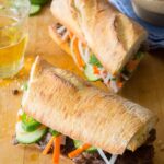 Lemongrass beef Bahn Mi sandwiches on a wooden cutting board.