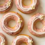 Close up of baked cherry doughnuts with cherry and vanilla glaze and white chocolate crispy balls.